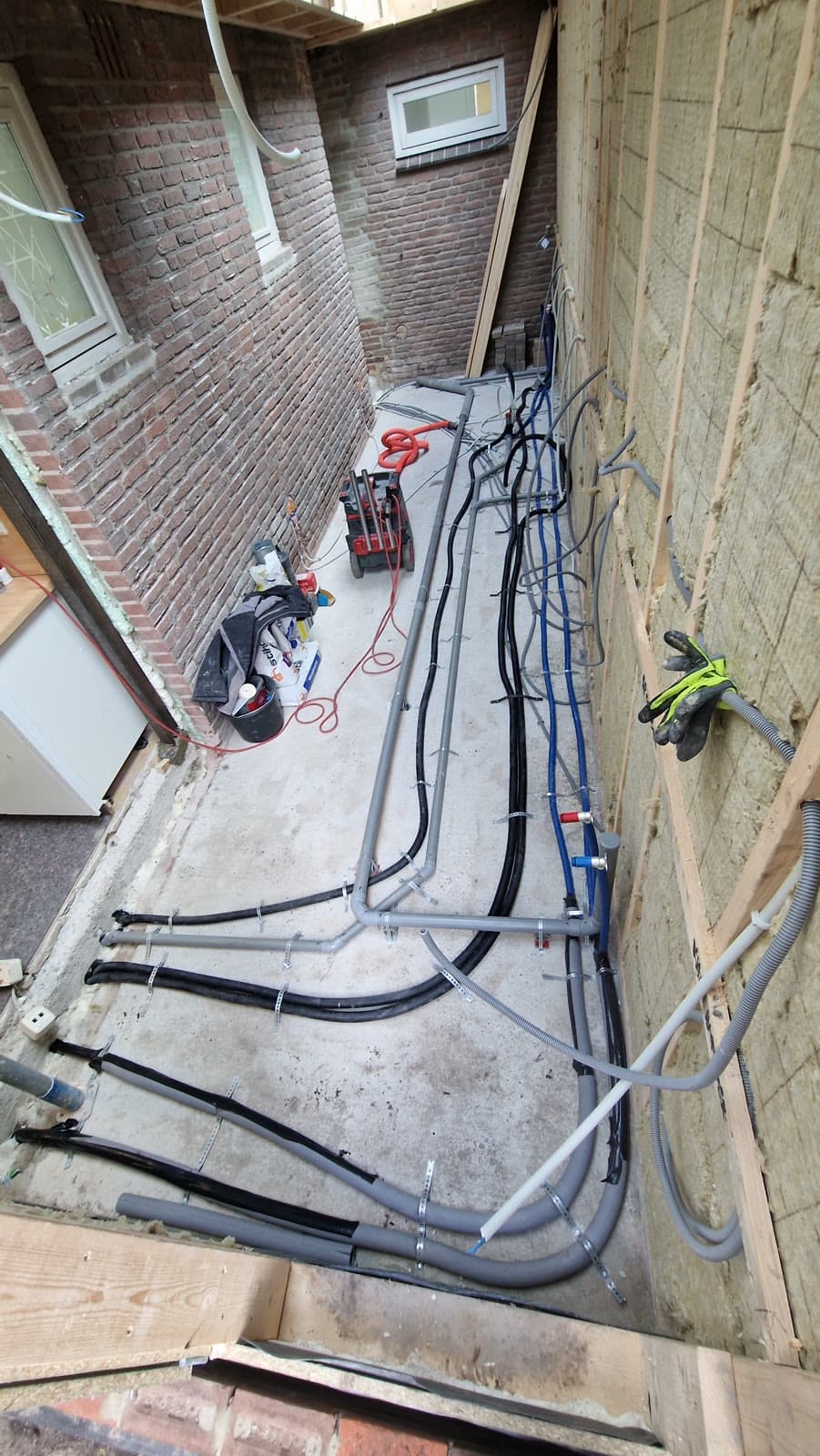 Leidingwerk over een betonvloer tijdens renovatie